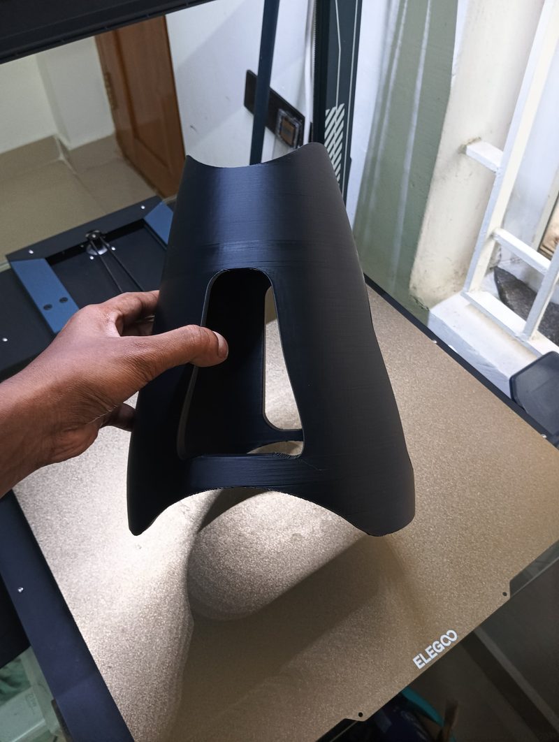 Large black 3D-printed cowling held above the printer bed